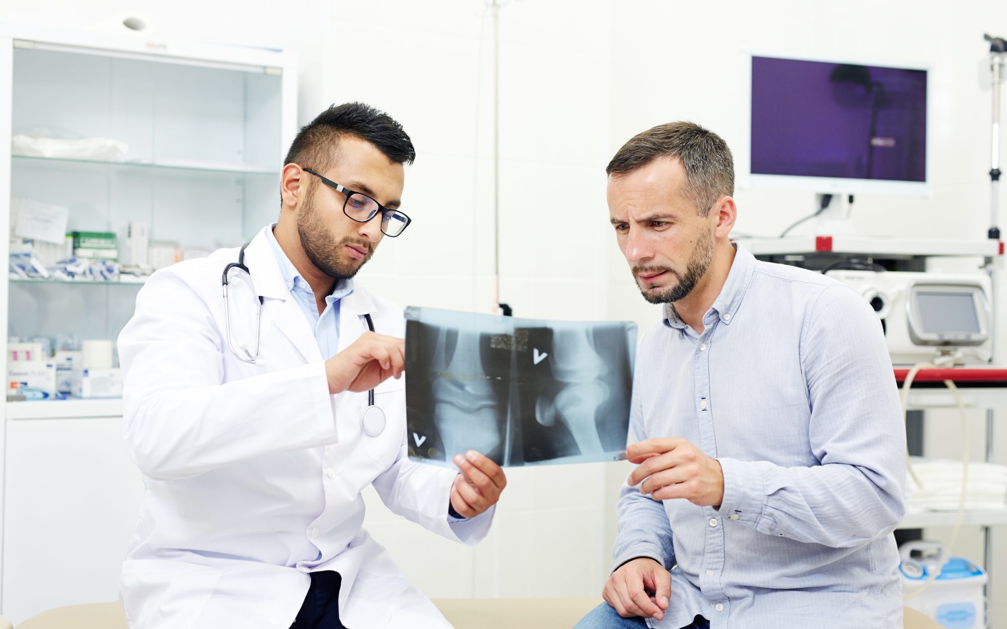 A surgeon going through x-ray images with a patient.